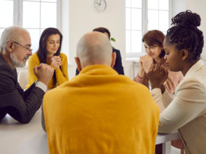 people sitting around table and praying