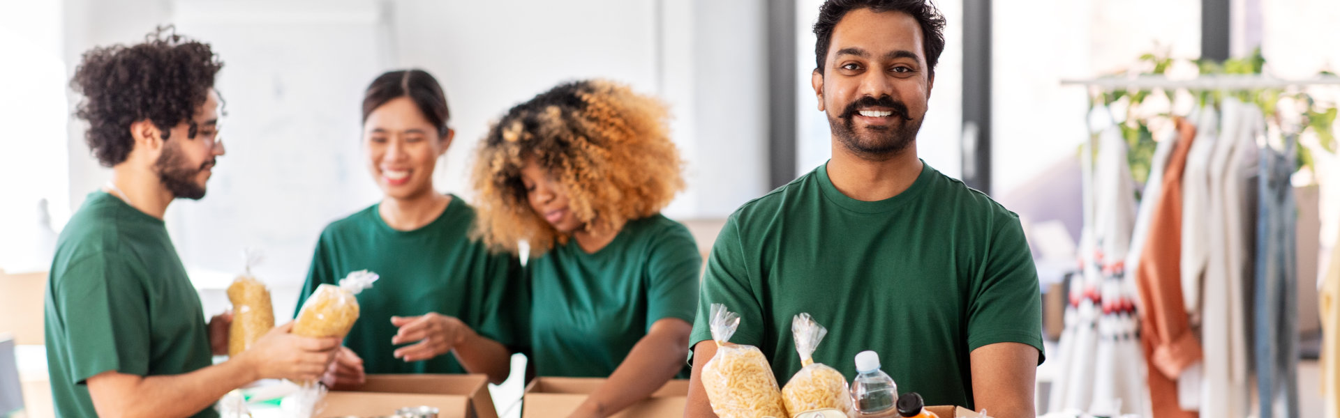 young man smiling while holding a food in a box